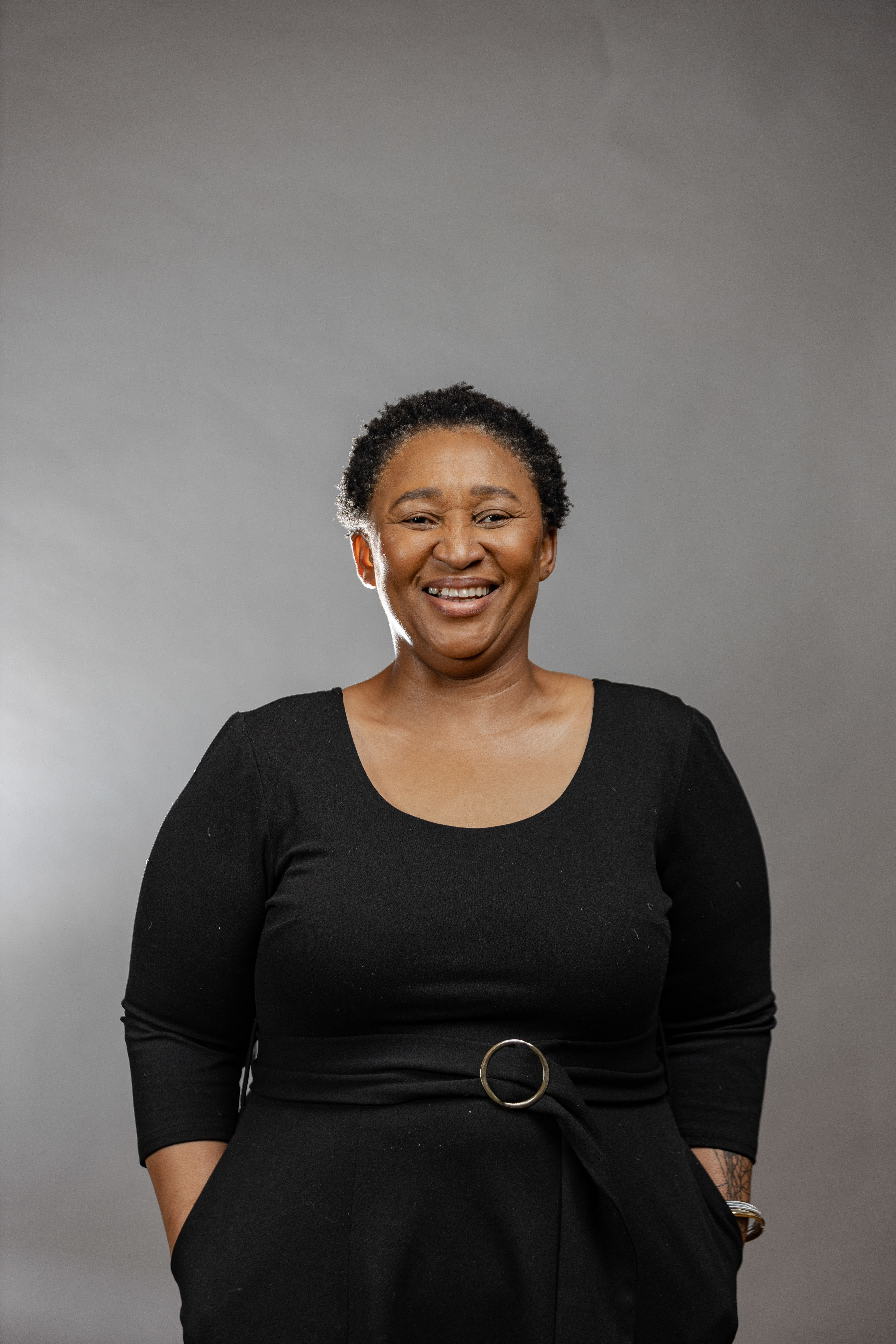 Portrait of a woman smiling wearing black with a grey background.