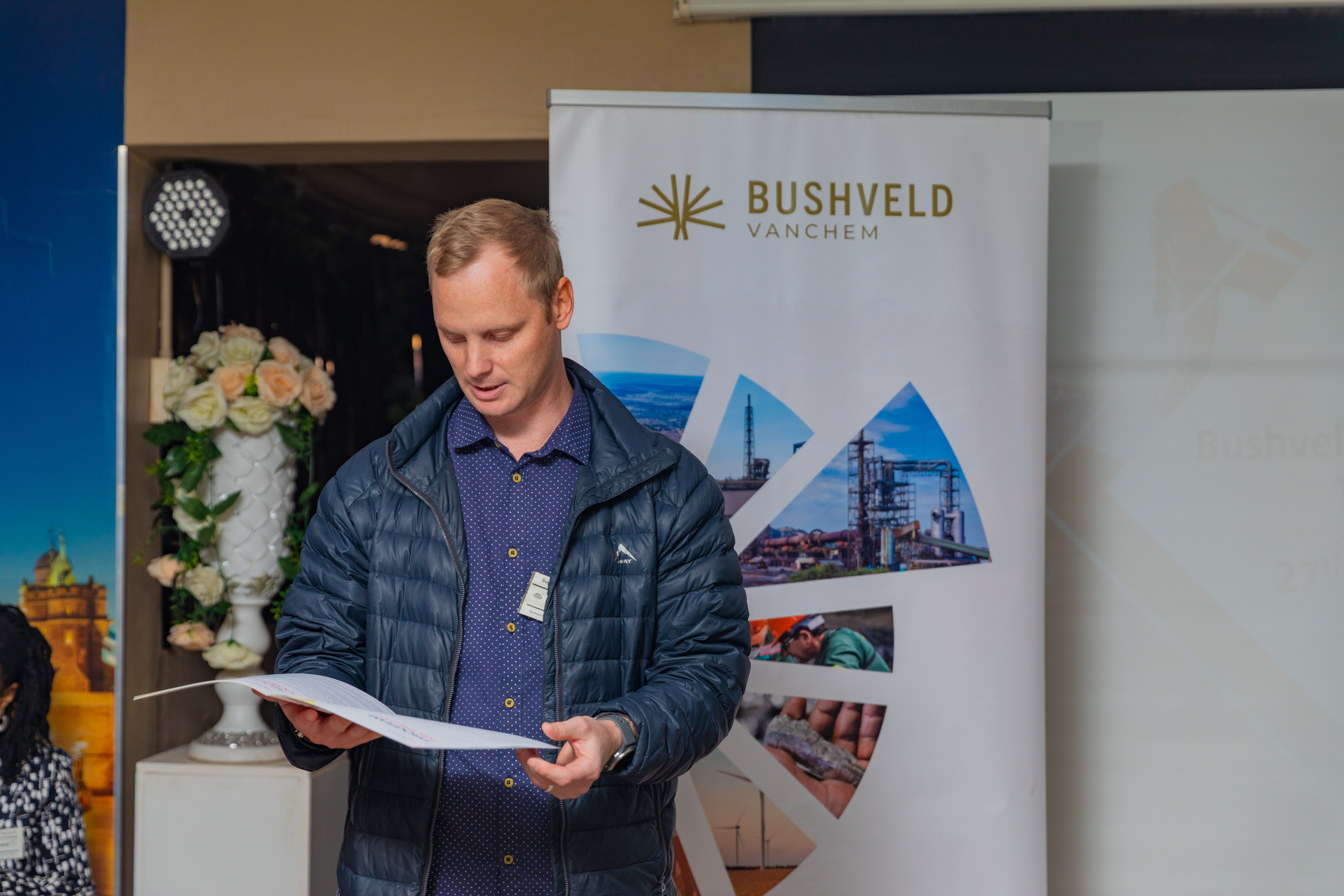 Man reading from paper standing in front of branding background